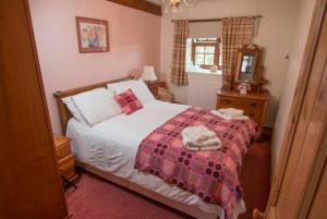 a bedroom with a bed with a red blanket and a mirror at Coach House, Gogarth in Machynlleth