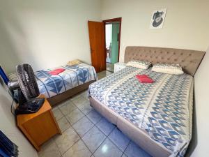 a bedroom with two beds and a television in it at Casa p/ 11 hóspedes - 900m do Parque de Exposições in Patos de Minas