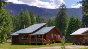 a log cabin in the woods with mountains in the background at Beatrice Place in Slocan