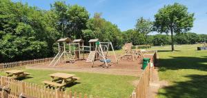 a park with a playground with tables and benches at Bell Tent Village Parks in Nottingham