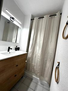 Un baño con lavabo y cortina de ducha. en Appartement vue sur mer Le Grau du Roi, en Le Grau-du-Roi