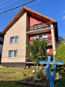 una casa con un cartel azul delante en Apartmán u zajaca v Liptovskom Trnovci, en Liptovský Trnovec