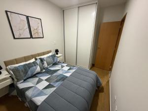 una camera da letto con un letto con una coperta a quadri di Lindo apto prox shopping a São João del Rei