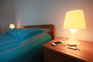 a bed with a table with a lamp and a tablet at Pleasant seaside accommodation in Rosolina Mare in Rosolina Mare
