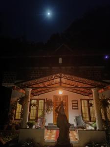 a woman in a dress standing in front of a house at night at Reevilla in Madikeri +22 photos