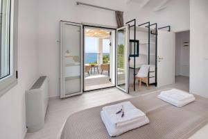 a white room with a bed and a view of the ocean at Tania Villas by PaxosRetreats in Gaios