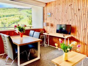 ein Zimmer mit einem Tisch und einem Schreibtisch mit Blumen darauf in der Unterkunft Gite Caribou in Besse-et-Saint-Anastaise