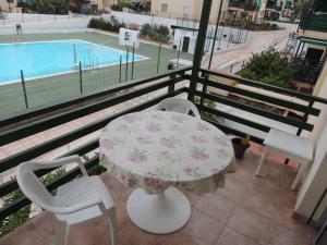 a balcony with a table and chairs and a pool at Accessible Cristimar in Los Cristianos