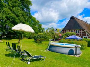a yard with a pool and chairs and an umbrella at Altes Landhaus Oste, Klavier Appartement, 2 Zimmer mit Kamin in Hemmoor