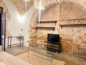 a living room with a tv and a brick wall at Kalma Arched Loft - Unique Brick Vault in City Heart in Cagliari +5 photos