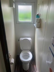 a small bathroom with a toilet and a window at Cozy bungalow in Ivry-la-Bataille +5 photos