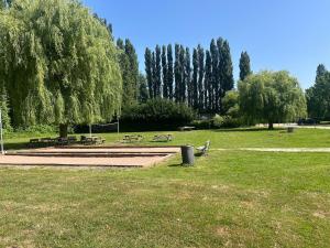 a park with benches and picnic tables in the grass at Cozy bungalow in Ivry-la-Bataille