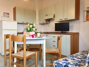 ロゾリーナ・マーレにあるApartment by the sea in Rosolina Mareのキッチン(小さなテーブル、椅子付)、キッチン(冷蔵庫付)