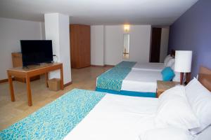 a hotel room with two beds and a television at Hotel Oceania Cartagena in Cartagena de Indias