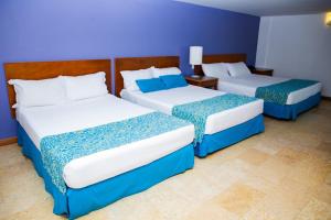 three beds in a room with blue walls at Hotel Oceania Cartagena in Cartagena de Indias