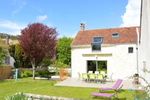 a house with a patio and purple chairs in the yard at Le jardin sainte anne in Balnot-sur-Laignes