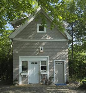 a gray house with two doors and two dogs at Walker Cottage in Rockport