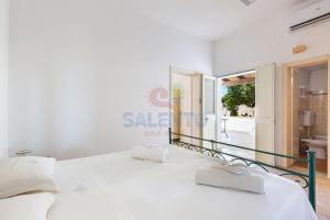 a bedroom with a white bed with asale sign on the wall at Salentoandmore - Villetta Salento in Marina San Gregorio