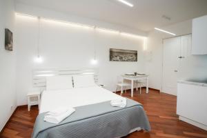 a white bedroom with a bed and a table at Due metri sopra al mare in Otranto