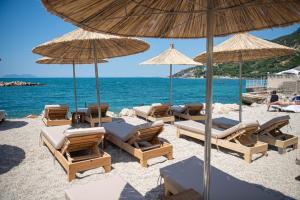 a group of chairs and umbrellas on a beach at White Hill by Fllad e Vale in Vlorë
