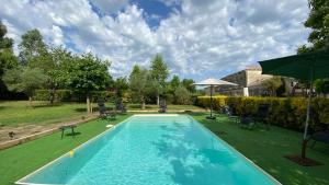 a swimming pool in a yard with chairs and an umbrella at Gîte de Moulins in Cézac