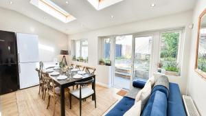 a kitchen and dining room with a table and a blue couch at Lovely 4-Bedroom Kilburn Flat with Garden and Parking near Hampstead Heath, Abbey Road in London