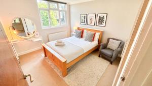 a small bedroom with a bed and a chair at Lovely 4-Bedroom Kilburn Flat with Garden and Parking near Hampstead Heath, Abbey Road in London