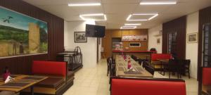a restaurant with tables and red chairs and a counter at Hotel Claudia in Macuspana