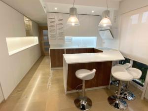 una cocina con una isla y dos taburetes en ella en Acogedor apartamento con acabados primera calidad, en Zaragoza