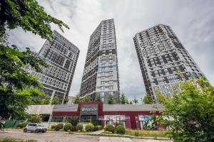 two tall buildings in a city with a parking lot at Petrovdom Apartments 18-100 in RC Poetika, 25E Degtyarivska Street, Building 3, First Collection in Kyiv