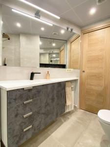 Un baño con lavabo, inodoro y espejo. en Acogedor apartamento con acabados primera calidad, en Zaragoza