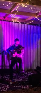 a man playing a guitar in a room with purple lights at Dartmoor Hotel Motel in Dartmoor