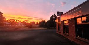 a building with a sunset in the background at Dartmoor Hotel Motel in Dartmoor
