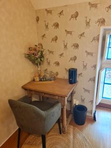 a table and a chair in a room with a wall at Chambre avec Charme & Jardin in Saint-Rémy-du-Plain
