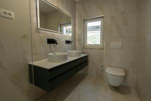 ein Badezimmer mit zwei Waschbecken und einer Toilette in der Unterkunft Bed & Breakfast Adelsberg Inn in Postojna