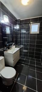 a black tiled bathroom with a toilet and a sink at Apartament Tiana in Mamaia Nord
