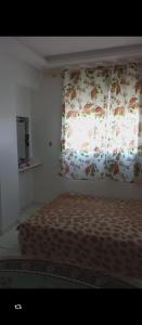a bedroom with a bed and a window with a curtain at El jadida in El Jadida
