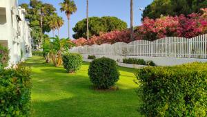 a white fence with bushes and trees in a yard at Apartamento Los Corrales in Rota