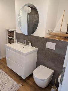a bathroom with a sink and a toilet and a mirror at Emden - Ferienwohnung mit Kanal-Blick in Emden +6 photos