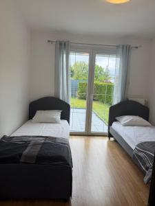 モンベリアルにあるMaison jardin barbecue parkingの窓付きの客室で、ベッド2台が備わります。