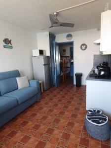 a living room with a blue couch and a kitchen at Studio vue Mer Ile des Pêcheurs in Cap d'Agde