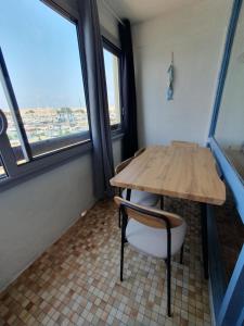 a table and a chair in a room with windows at Studio vue Mer Ile des Pêcheurs in Cap d'Agde +1 photo
