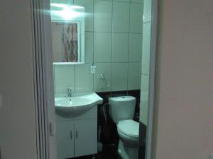 a white bathroom with a toilet and a sink at The Garden Apartments in Nea Kallikrateia