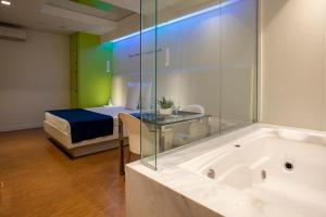a bathroom with a tub and a bed in a room at Izzi Motel 2 in Sao Paulo