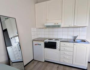 a kitchen with white cabinets and a stove and a refrigerator at Kasarminkadun Basic Cozy 19,5 m2 in Vaasa