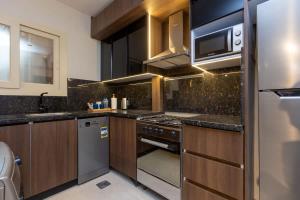 Una cocina con gabinetes de madera y electrodomésticos de acero inoxidable. en Luxury 2 BR - 1 Ensuite- POOL - By Beithady - BH-26-102, en New cairo