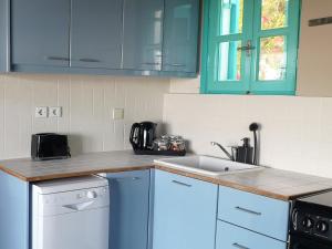a kitchen with blue cabinets and a sink at The Iconpainter Peroulia Villa in Kómboi