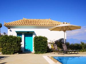 a house with a green door and an umbrella at The Iconpainter Peroulia Villa in Kómboi +3 photos