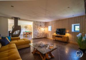 ein Wohnzimmer mit Sofa und Fernseher in der Unterkunft Mas des Glycines in Saint-Montan