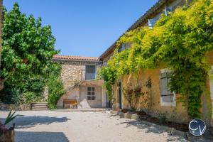 ein altes Steinhaus mit einem Innenhof und Bäumen in der Unterkunft Mas des Glycines in Saint-Montan